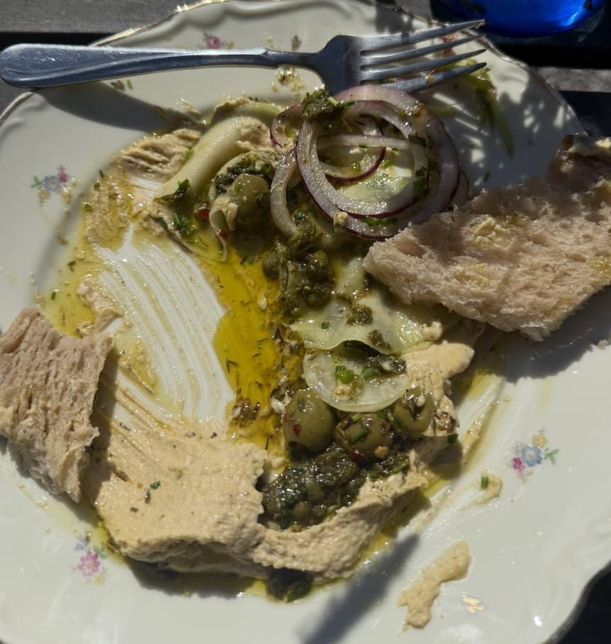 The same dish half-eaten, with green olives and capers visible through the salsa verde