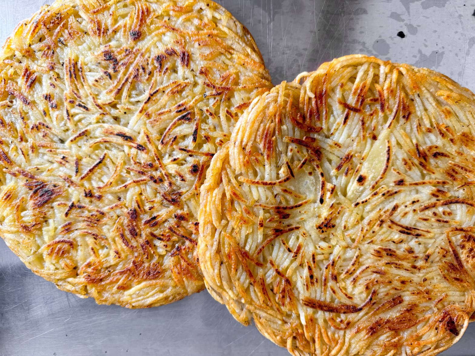 Two crisp, golden-brown pommes darphin potato cakes